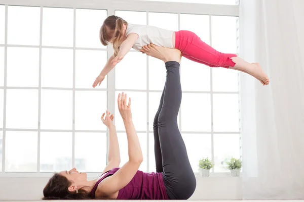 Ung mor och dotter gör yoga övning — Stockfoto