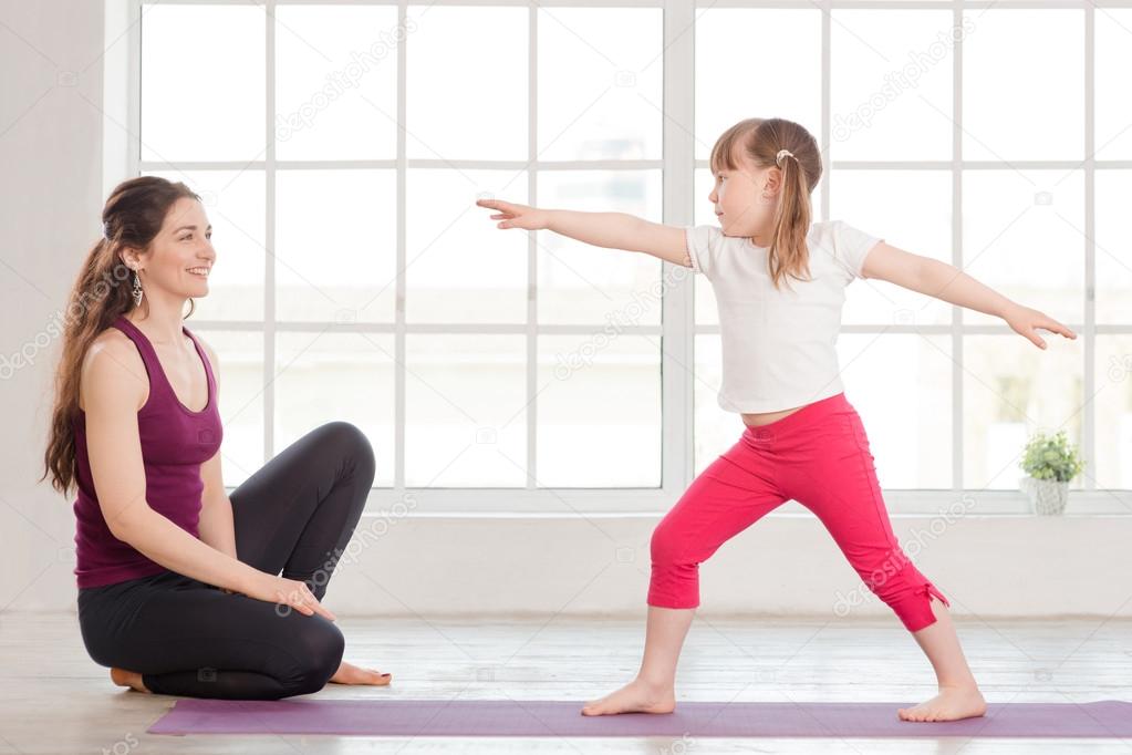 Young mother and daughter doing yoga exercise