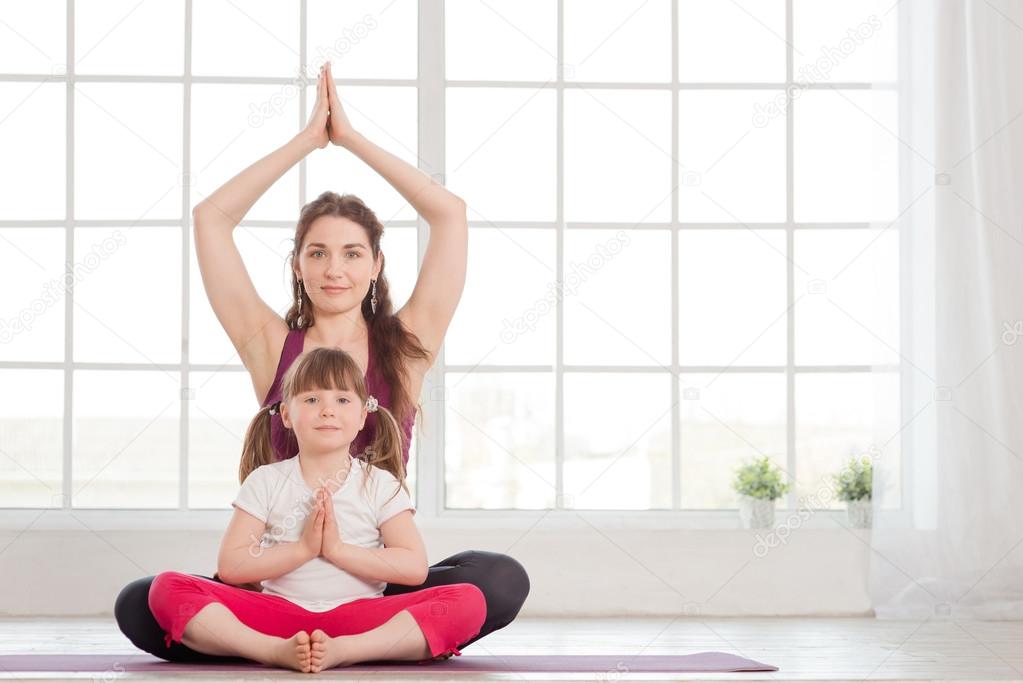 Young mother and daughter sitting in lotus position