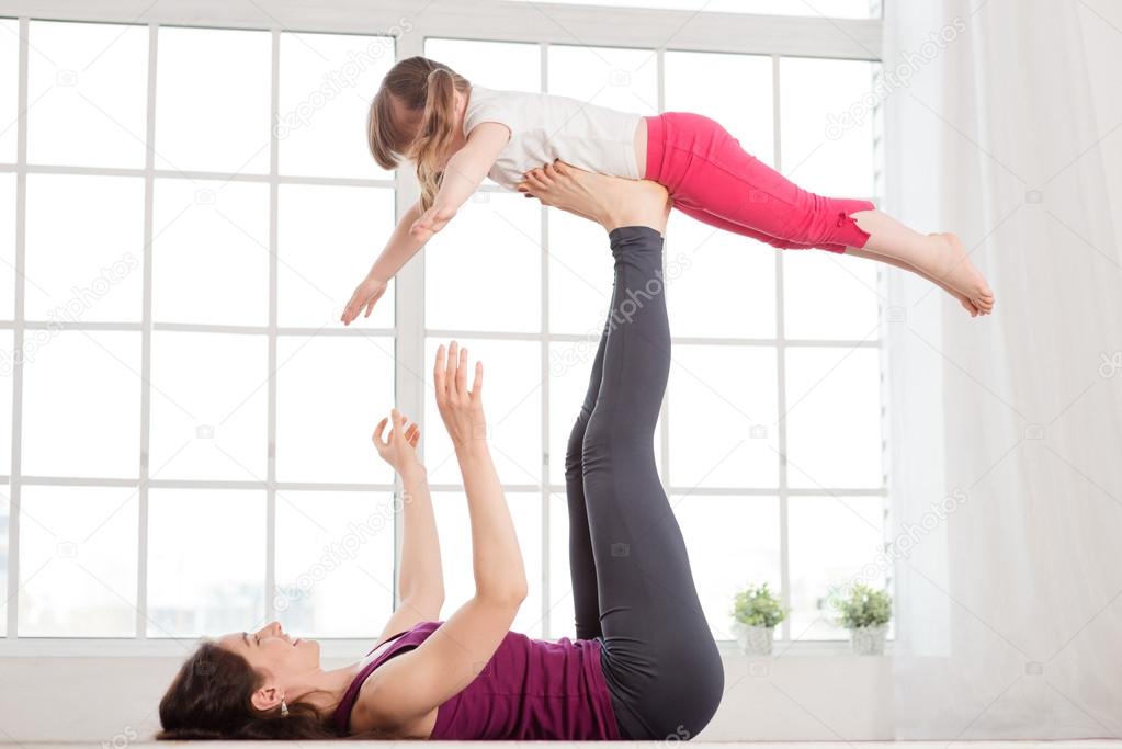 Young mother and daughter doing yoga exercise