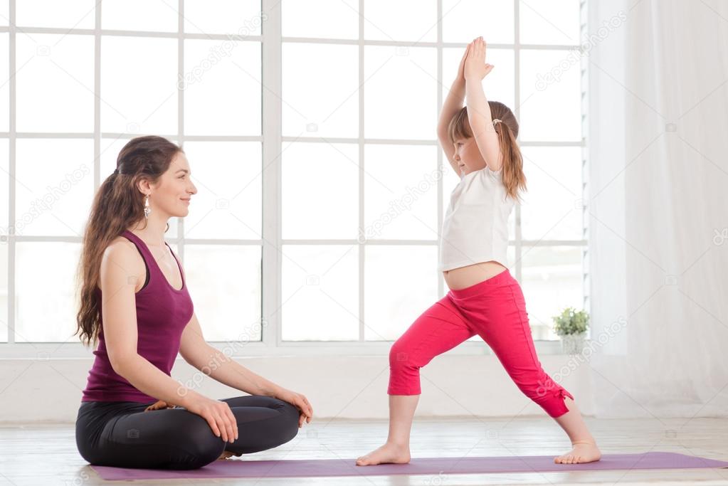 Young mother and daughter doing yoga exercise