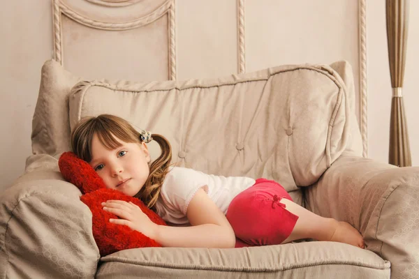 Sleepy little girl looking at camera in chair — Stock Photo, Image