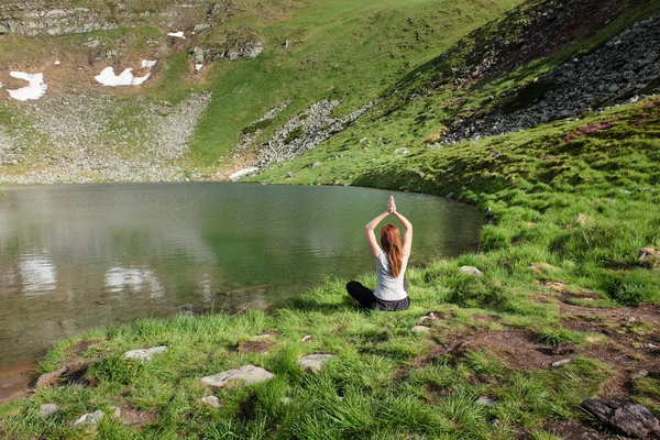 Young woman doing yoga exercises near lake — Stock Fotó