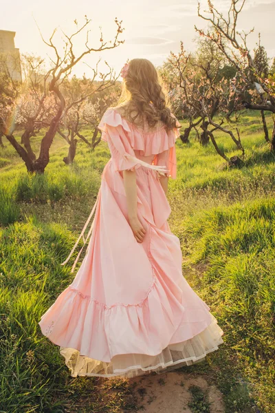 Aantrekkelijke vrouw wandelen in de tuin bloei op zonsondergang — Stockfoto