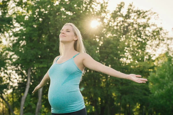 Mujer embarazada haciendo ejercicios de yoga sobre la naturaleza — Foto de Stock