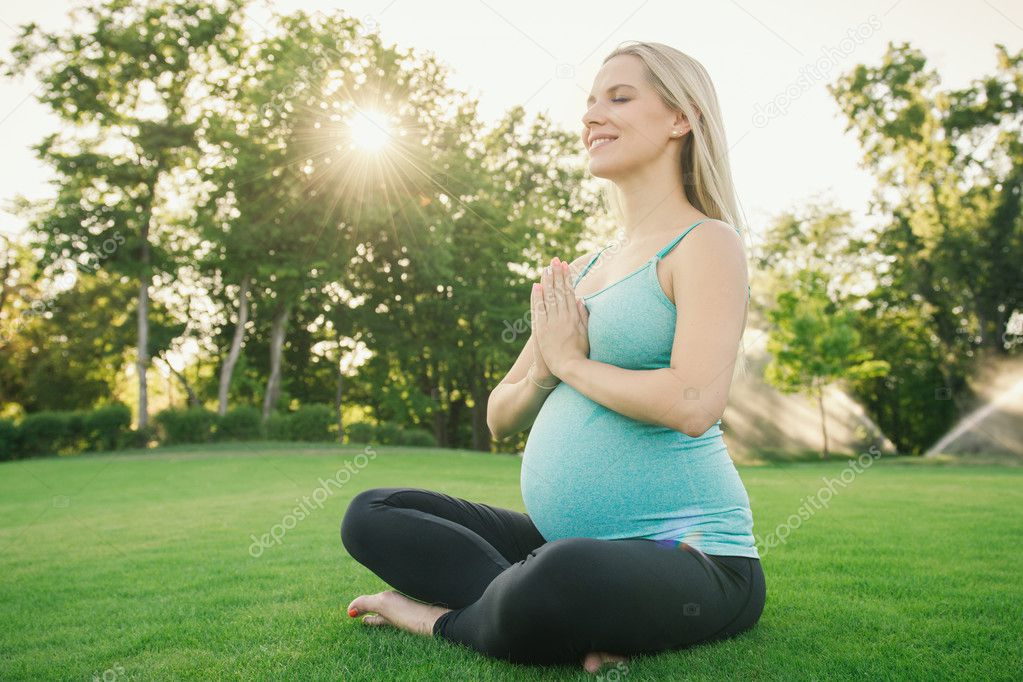 Pregnant woman doing yoga exercises on the nature