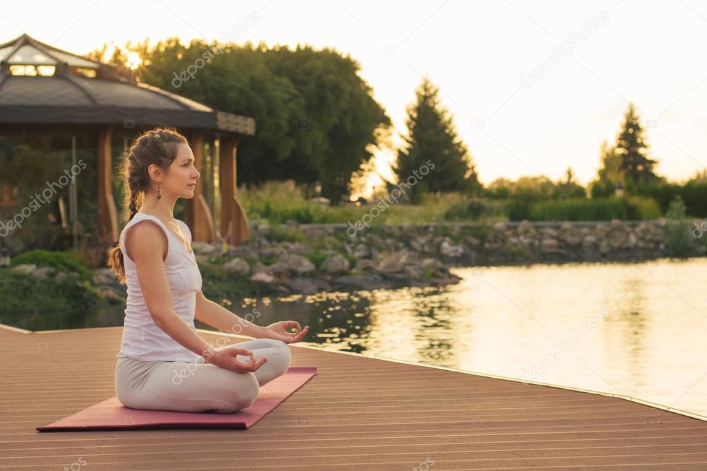 Woman meditating near lake