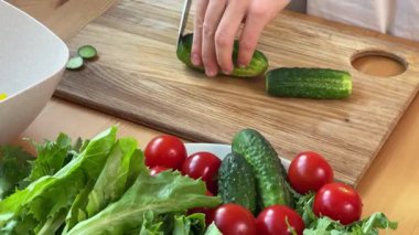 Yetenekli bir şef lezzetli ve sağlıklı bir yemek yapmak için taze salatalık ve olgun domates hazırlar.