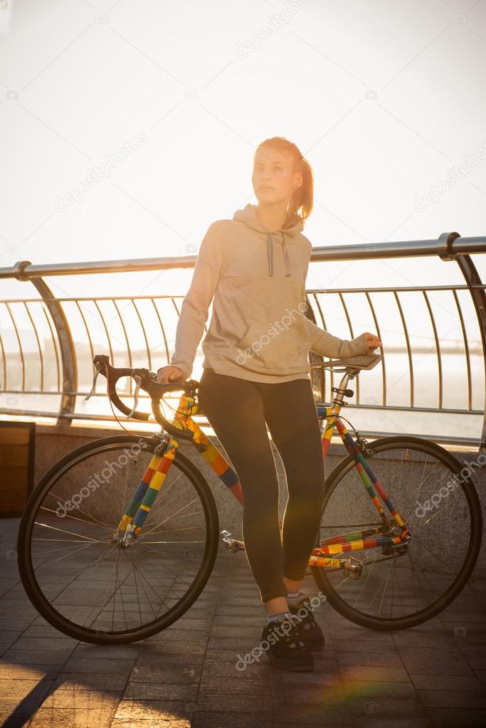 Young woman and bike in the morning city