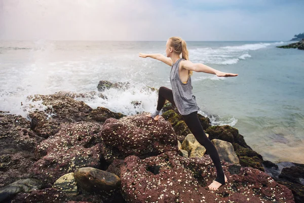 Ejercicio de yoga en el acantilado del mar al atardecer — Foto de Stock