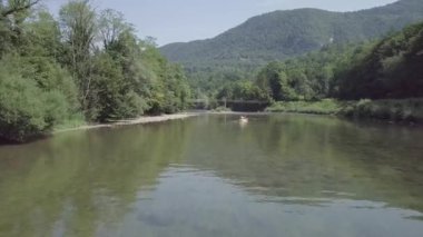 Slovenya 'daki Kolpa nehrinde eski bir ahşap köprünün altında kayak yaparken. 4K