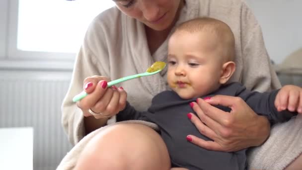 Un lindo bebé comiendo verduras verdes mixtas con mamá sosteniendo la cuchara 4K — Vídeo de stock