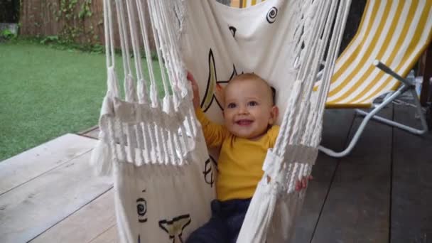 A cute baby boy smiling and swinging in a hammock outside. 4K — Stock Video