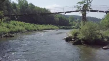 Slovenya 'daki Kolpa nehrinde eski bir ahşap köprünün altında kayak yaparken. 4K