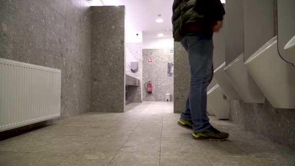 Egy férfi, aki nyilvános vécére megy vizelni, aztán kezet mos. — Stock videók