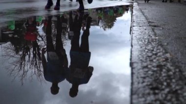 Maraton koşucularının yansıması. Yavaş çekimde bir su birikintisine adım atan bir adam.