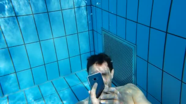 Mężczyzna piszący i robiący zdjęcia telefonem pod wodą w basenie — Wideo stockowe