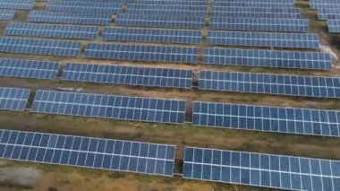 Güneşli bir günde bir tarlada güneş enerjisi santrali. Kuş bakışı. Güneş panelleri enerji üretimi alanında çizgide. Bir dron güneş çiftliğinin üzerinden uçuyor. Yenilenebilir yeşil enerji. Alternatif enerji kaynakları.