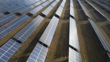 Güneşli bir günde bir tarlada güneş enerjisi santrali. Kuş bakışı. Güneş panelleri enerji üretimi alanında çizgide. Bir dron güneş çiftliğinin üzerinden uçuyor. Yenilenebilir yeşil enerji. Alternatif enerji kaynakları.