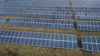 Güneşli bir günde bir tarlada güneş enerjisi santrali. Kuş bakışı. Güneş panelleri enerji üretimi alanında çizgide. Bir dron güneş çiftliğinin üzerinden uçuyor. Yenilenebilir yeşil enerji. Alternatif enerji kaynakları.
