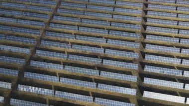 Güneşli bir günde bir tarlada güneş enerjisi santrali. Kuş bakışı. Güneş panelleri enerji üretimi alanında çizgide. Bir dron güneş çiftliğinin üzerinden uçuyor. Yenilenebilir yeşil enerji. Alternatif enerji kaynakları.