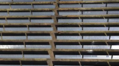 Güneşli bir günde bir tarlada güneş enerjisi santrali. Kuş bakışı. Güneş panelleri enerji üretimi alanında çizgide. Bir dron güneş çiftliğinin üzerinden uçuyor. Yenilenebilir yeşil enerji. Alternatif enerji kaynakları.