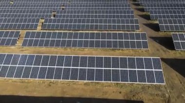 Güneşli bir günde bir tarlada güneş enerjisi santrali. Kuş bakışı. Güneş panelleri enerji üretimi alanında çizgide. Bir dron güneş çiftliğinin üzerinden uçuyor. Yenilenebilir yeşil enerji. Alternatif enerji kaynakları.