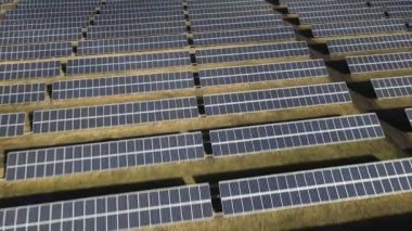 Güneşli bir günde bir tarlada güneş enerjisi santrali. Kuş bakışı. Güneş panelleri enerji üretimi alanında çizgide. Bir dron güneş çiftliğinin üzerinden uçuyor. Yenilenebilir yeşil enerji. Alternatif enerji kaynakları.