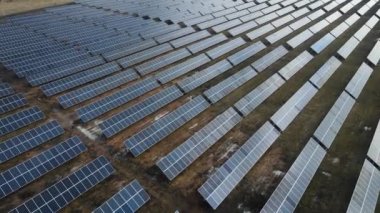 Güneşli bir günde bir tarlada güneş enerjisi santrali. Kuş bakışı. Güneş panelleri enerji üretimi alanında çizgide. Bir dron güneş çiftliğinin üzerinden uçuyor. Yenilenebilir yeşil enerji. Alternatif enerji kaynakları.