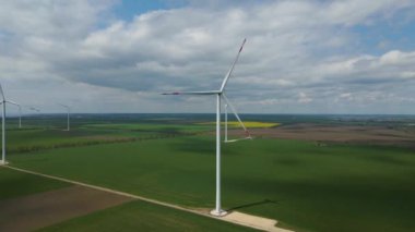 Geniş rüzgar türbinleri. Havadan bakıldığında mavi gökyüzü parkı yavaş çekim drone dönüşü. Yel değirmenlerinin siluetleri, yaz lensleri. alternatif enerji