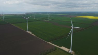 Geniş rüzgar türbinleri. Havadan bakıldığında mavi gökyüzü parkı yavaş çekim drone dönüşü. Yel değirmenlerinin siluetleri, yaz lensleri. alternatif enerji