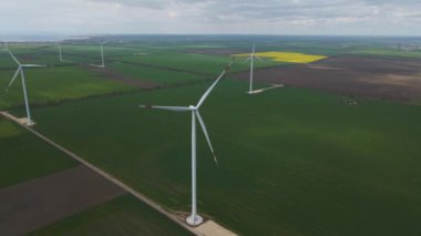 Geniş rüzgar türbinleri. Havadan bakıldığında mavi gökyüzü parkı yavaş çekim drone dönüşü. Yel değirmenlerinin siluetleri, yaz lensleri. alternatif enerji