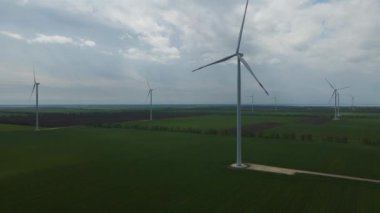 Geniş rüzgar türbinleri. Havadan bakıldığında mavi gökyüzü parkı yavaş çekim drone dönüşü. Yel değirmenlerinin siluetleri, yaz lensleri. alternatif enerji