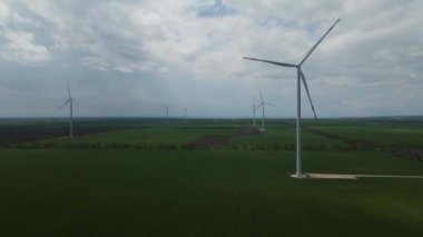 Geniş rüzgar türbinleri. Havadan bakıldığında mavi gökyüzü parkı yavaş çekim drone dönüşü. Yel değirmenlerinin siluetleri, yaz lensleri. alternatif enerji