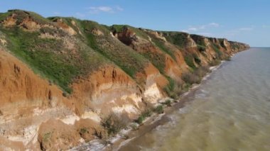 Deniz taşlarıyla dolu güzel kayalık sahil manzarası. Güneşli bir yaz gününde insansız hava aracıyla güzel bir hava manzarası. Kamp turizmi konsepti. 4k video