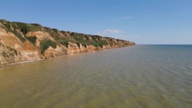 Deniz taşlarıyla dolu güzel kayalık sahil manzarası. Güneşli bir yaz gününde insansız hava aracıyla güzel bir hava manzarası. Kamp turizmi konsepti. 4k video