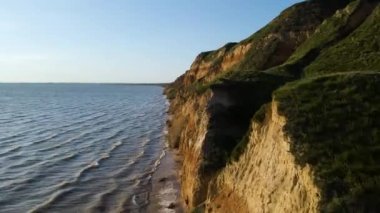 Deniz taşlarıyla dolu güzel kayalık sahil manzarası. Güneşli bir yaz gününde insansız hava aracıyla güzel bir hava manzarası. Kamp turizmi konsepti. 4k video