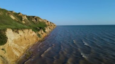 Deniz taşlarıyla dolu güzel kayalık sahil manzarası. Güneşli bir yaz gününde insansız hava aracıyla güzel bir hava manzarası. Kamp turizmi konsepti. 4k video