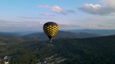 Güneşin doğuşuyla dağın üzerinde renkli sıcak hava balonu uçuyor. Güzel bir gökyüzü var. İHA 'nın yüksek irtifa uçuşunu geniş açıdan görebiliyoruz.