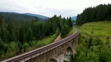 Eski dizel tren demiryolu şeridi boyunca ilerliyor. Güzel orman manzaralı dağlar.
