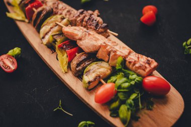 Tahta bir arka planda taze sebzeli tavuk ve sebze şişleri.