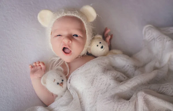 Ağlayan beyaz şapkalı yeni doğmuş bebek.