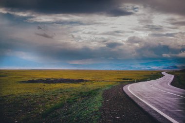 Dağlarda eğlenme kavramı. Dağ vadisinde asfalt bir yol. Bulutlardaki dağların arka planında. 