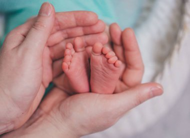 Annem prematüre bir bebeğin küçük bacaklarını elinde tutuyor.. 