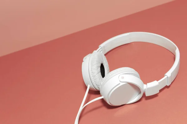 White headphones on a rose background
