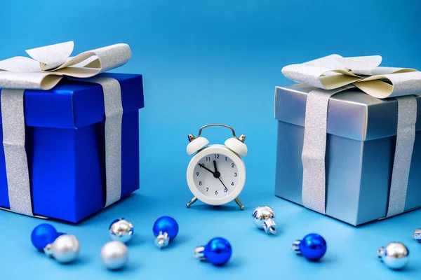boxes with gifts and christmas tree blue toys with clock on blue background,