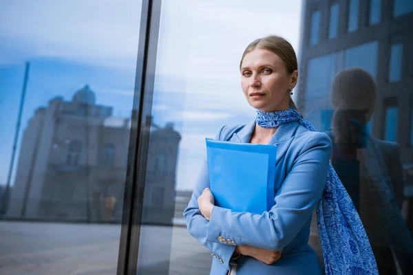 Business woman with folder in hand near office building