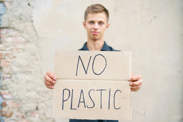 Young man with the inscription on the cardboard no plastic.