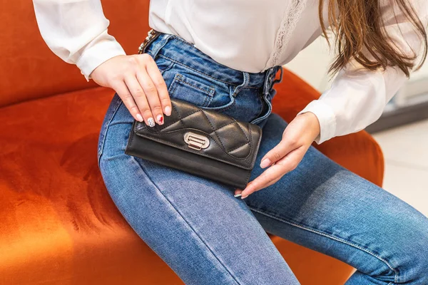 Menina de jeans segura uma bolsa preta — Fotografia de Stock