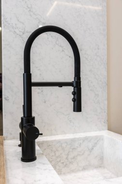 Modern mutfak detayı, beyaz mermer lavabo ve arkaplan üzerinde siyah kazak musluğu, temiz minimalist ev yenileme tarzı gösteren.